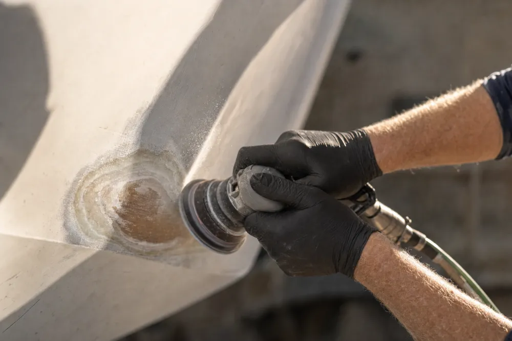 Damaged fibreglass being ground back to a clean taper on a white hull